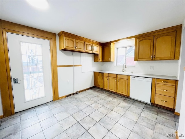 kitchen featuring baseboards, dishwasher, light countertops, brown cabinetry, and a sink