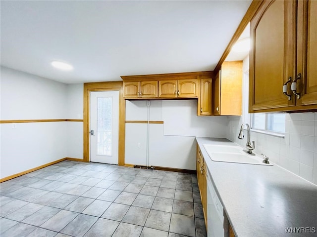 kitchen featuring light countertops, tasteful backsplash, baseboards, and a sink