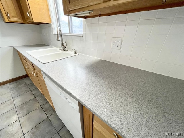 kitchen featuring brown cabinetry, light tile patterned flooring, white dishwasher, a sink, and decorative backsplash