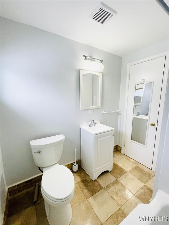 bathroom featuring visible vents, baseboards, toilet, and vanity