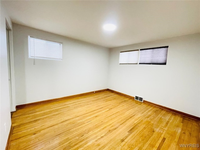 empty room with wood finished floors, visible vents, and baseboards