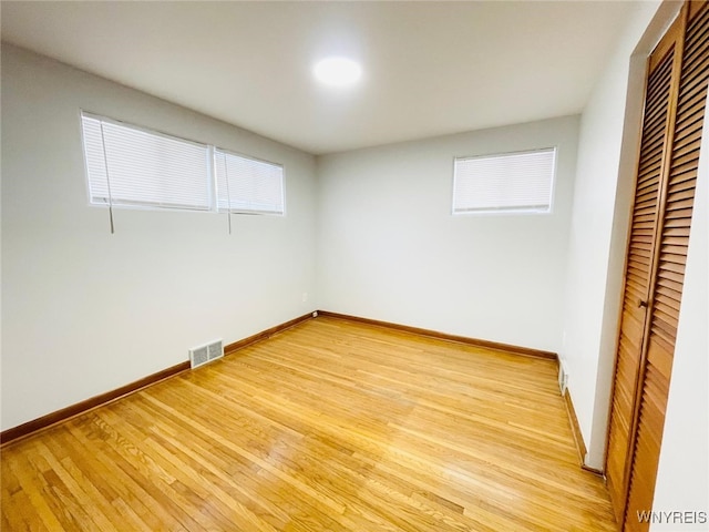 unfurnished bedroom featuring light wood-type flooring, visible vents, baseboards, and a closet