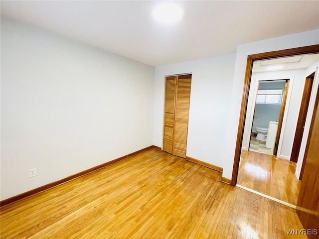 unfurnished bedroom featuring a closet, baseboards, and light wood finished floors