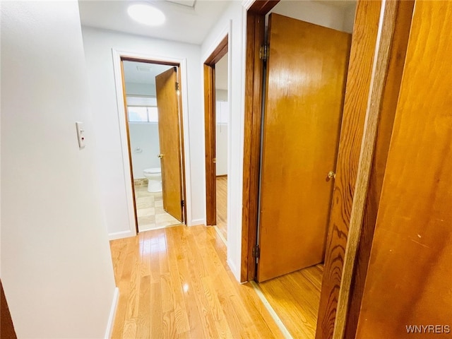 hallway with light wood-type flooring and baseboards