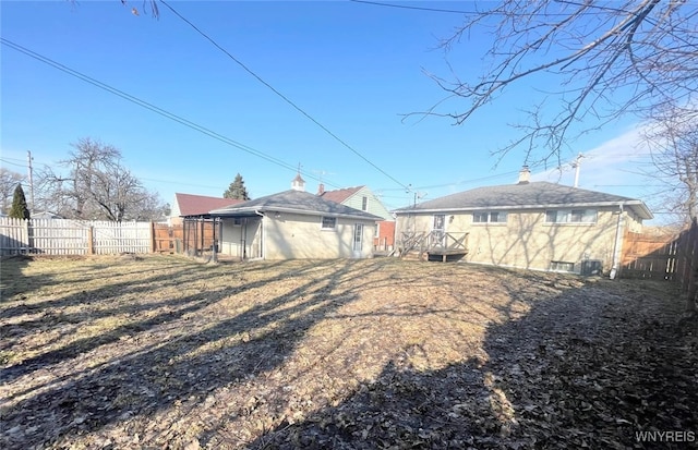 rear view of house featuring an outdoor structure and fence