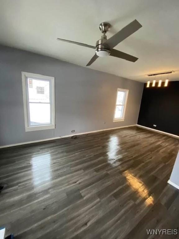 spare room with ceiling fan, dark wood-type flooring, and baseboards