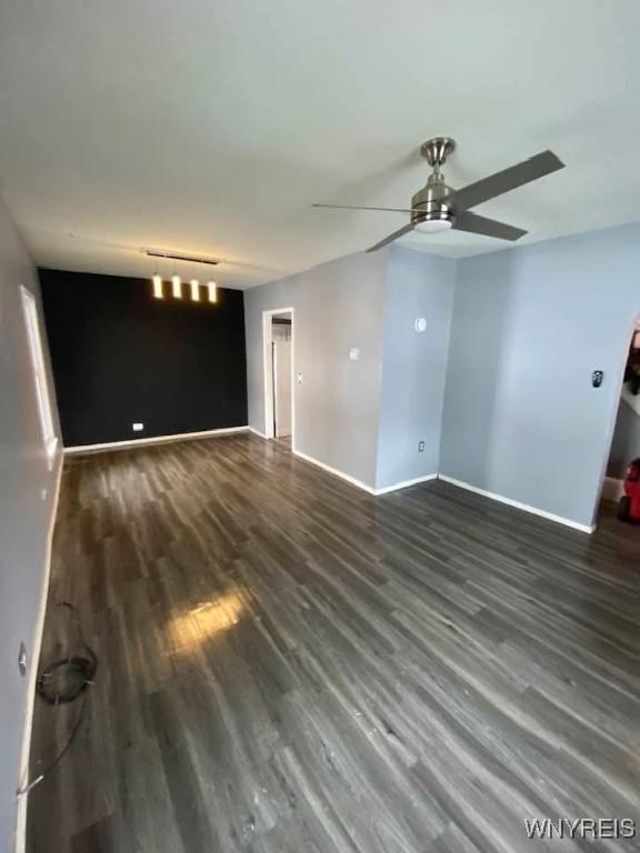 unfurnished living room with ceiling fan, baseboards, and wood finished floors