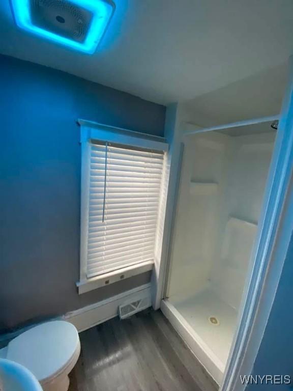 bathroom with a shower stall, toilet, and wood finished floors