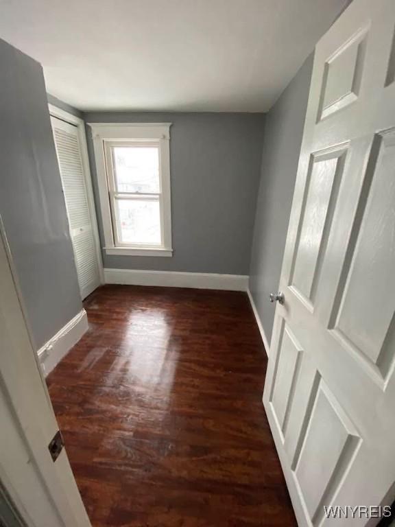 unfurnished bedroom with a closet, baseboards, and wood finished floors