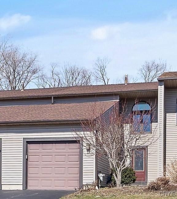 view of front of home featuring driveway and roof with shingles