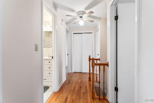 hall with baseboards, light wood finished floors, and a sink