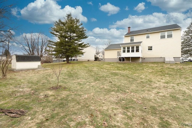 rear view of house with a chimney, a yard, a sunroom, an outbuilding, and a storage unit