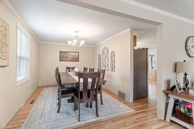 dining space with light wood-style flooring, a healthy amount of sunlight, and ornamental molding