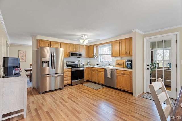 kitchen featuring light countertops, light wood-style flooring, ornamental molding, and stainless steel appliances