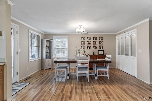 dining space featuring visible vents, light wood-style flooring, and crown molding