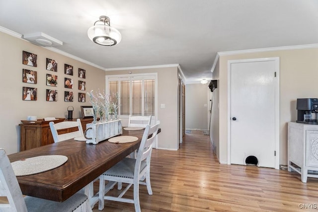 dining room featuring light wood-style flooring and crown molding