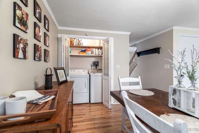 clothes washing area featuring washer and clothes dryer, laundry area, light wood finished floors, and crown molding