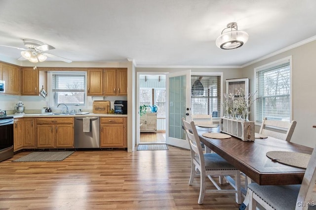 kitchen with a sink, stainless steel appliances, light countertops, crown molding, and light wood-type flooring