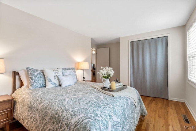 bedroom with visible vents, baseboards, and wood finished floors