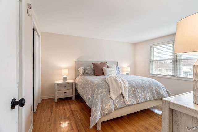 bedroom featuring light wood-style flooring, baseboards, and a closet