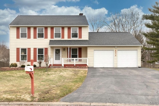 view of front of home with a front lawn, driveway, covered porch, a garage, and a chimney