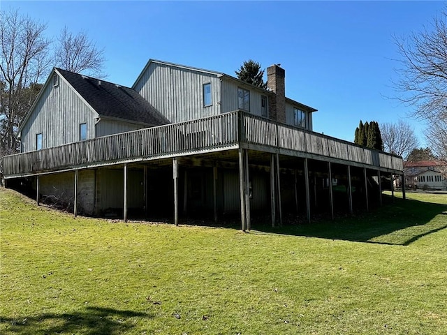 back of property with a deck, a yard, and a chimney