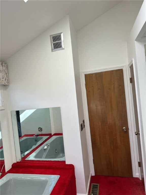 hall featuring a sink, visible vents, and lofted ceiling