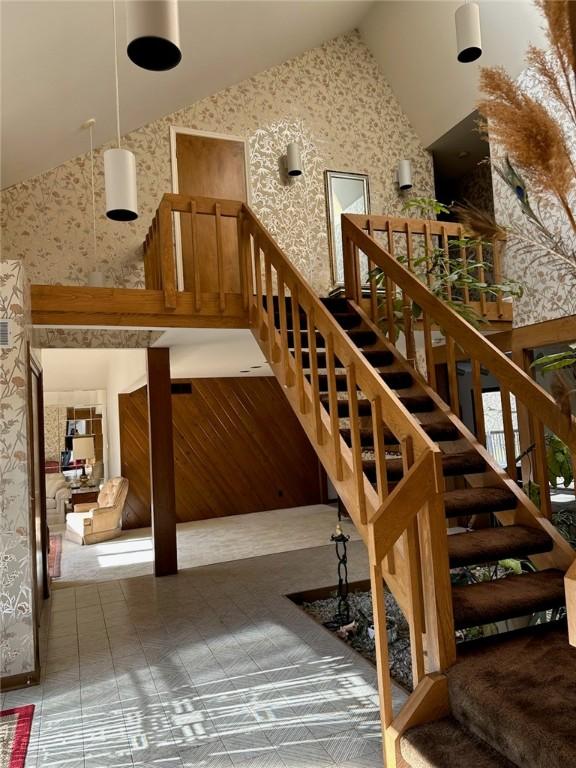 stairway with high vaulted ceiling and wallpapered walls