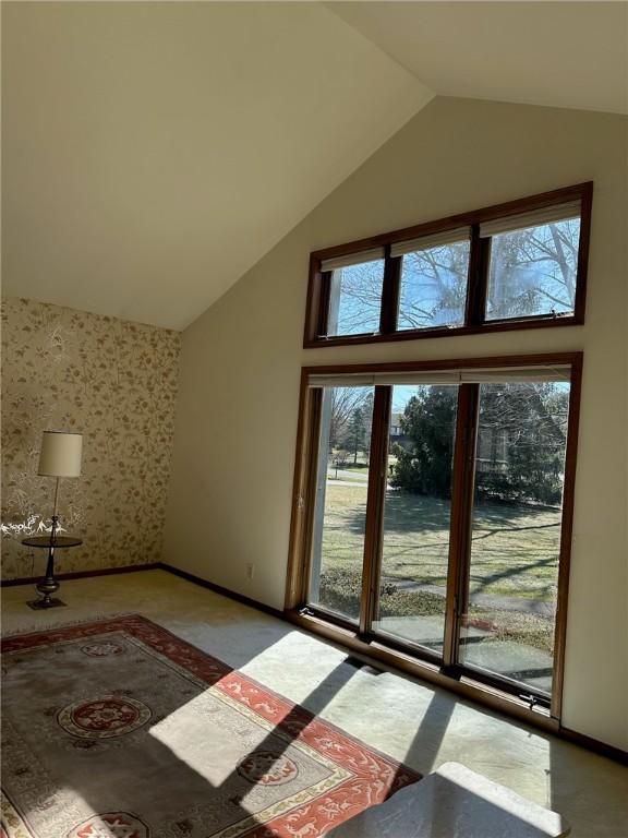 entryway with wallpapered walls, baseboards, and high vaulted ceiling