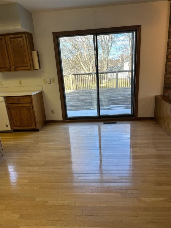 unfurnished dining area with light wood-style flooring, baseboards, and visible vents