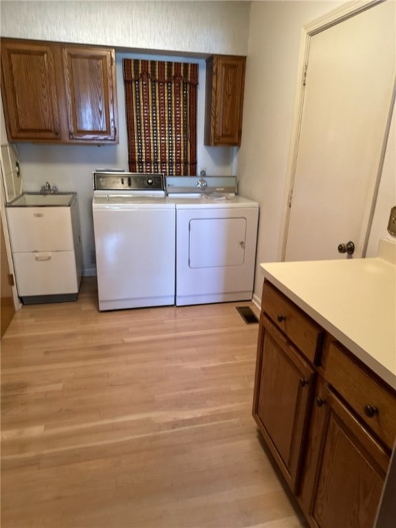 laundry room featuring cabinet space, separate washer and dryer, and light wood finished floors