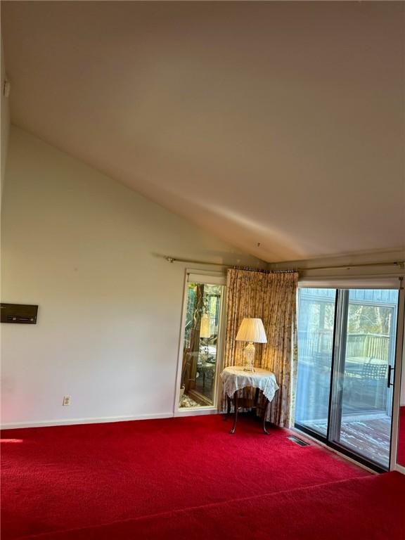 unfurnished room featuring baseboards, lofted ceiling, and carpet floors