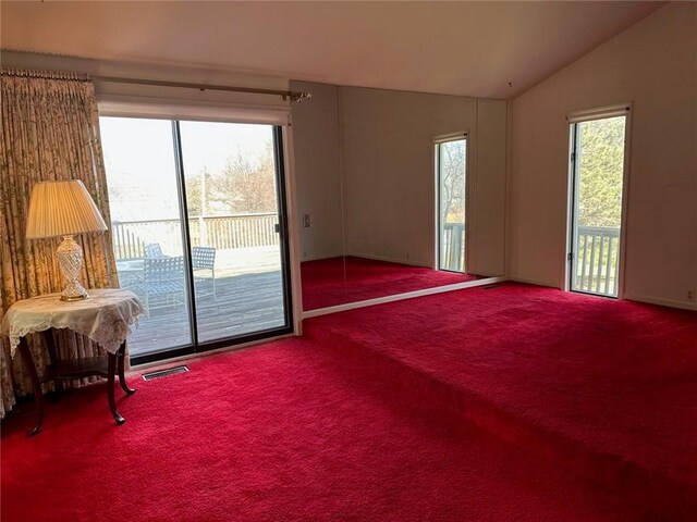 interior space featuring visible vents, carpet flooring, and vaulted ceiling