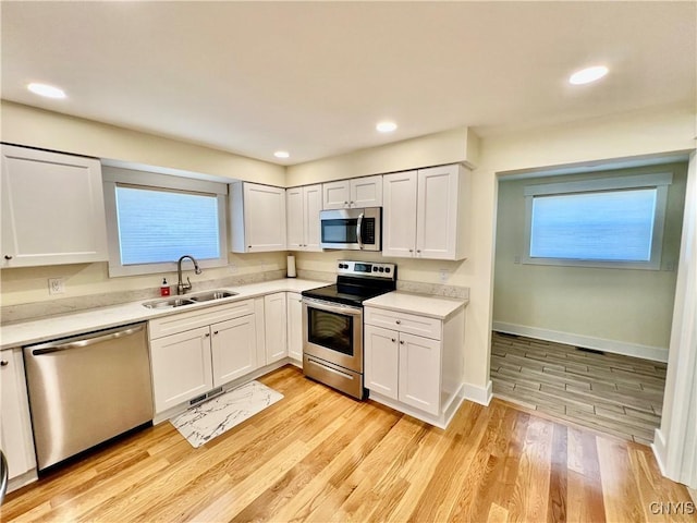 kitchen with a sink, stainless steel appliances, light countertops, and light wood finished floors