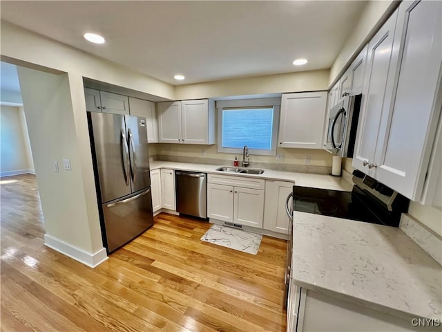 kitchen featuring a sink, recessed lighting, appliances with stainless steel finishes, light wood finished floors, and baseboards