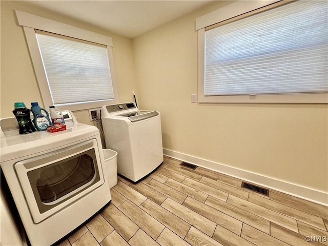 laundry room with baseboards, visible vents, wood finish floors, laundry area, and washer and clothes dryer