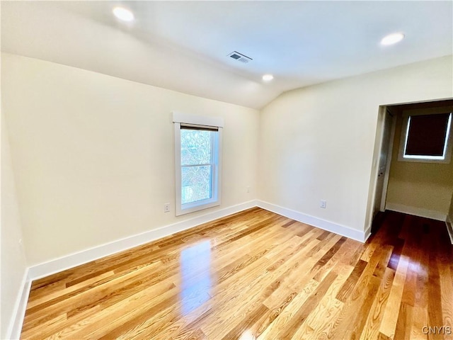 unfurnished room with visible vents, baseboards, lofted ceiling, and light wood finished floors