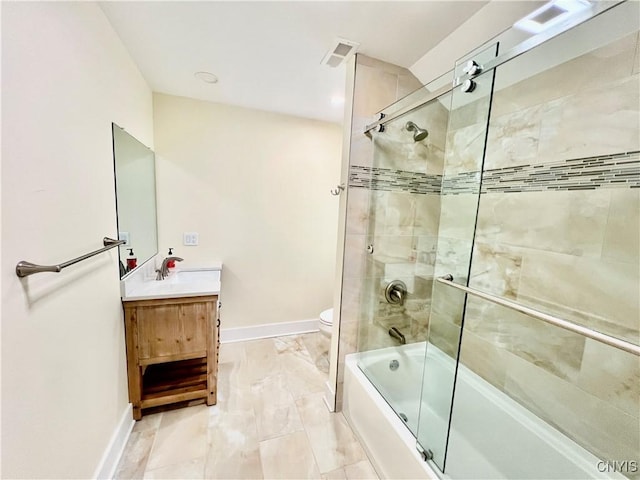 bathroom featuring vanity, toilet, baseboards, and bath / shower combo with glass door