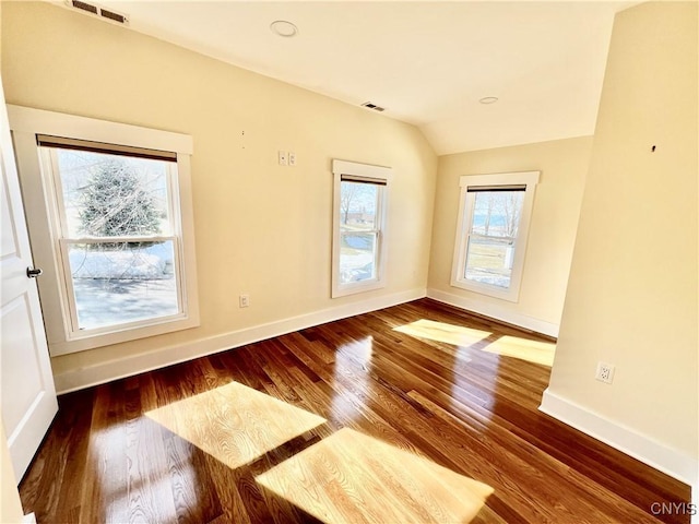 spare room featuring visible vents, lofted ceiling, baseboards, and wood finished floors