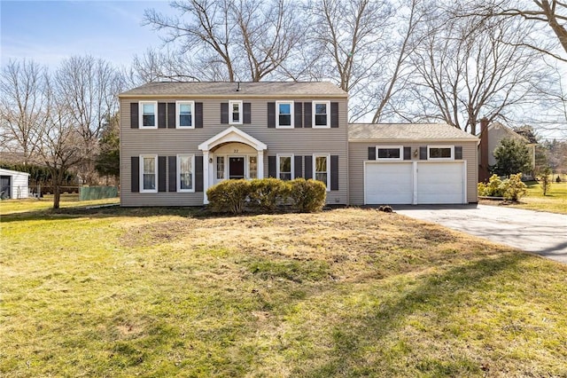 colonial-style house featuring a front yard, an attached garage, and driveway