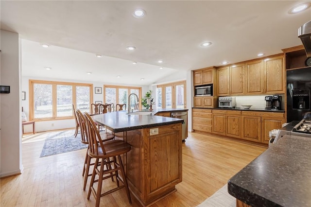 kitchen featuring light wood-style flooring, a sink, a spacious island, recessed lighting, and stainless steel appliances