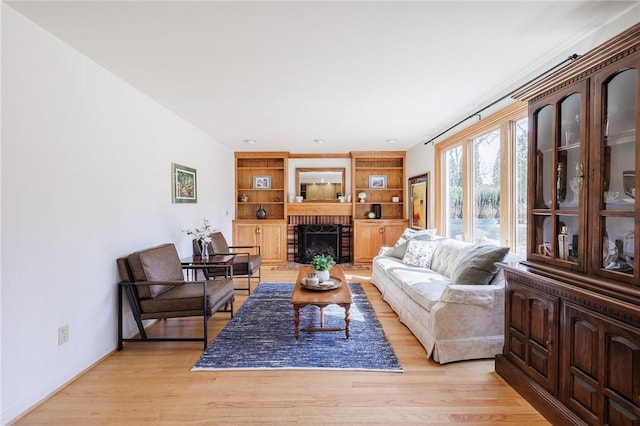 living area featuring a fireplace, baseboards, and light wood-style floors