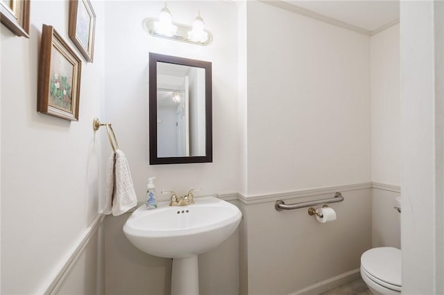 half bathroom featuring toilet and crown molding