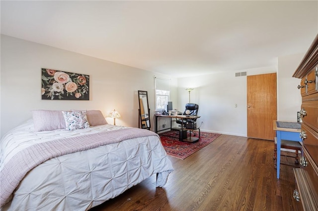 bedroom with wood finished floors, visible vents, and baseboards