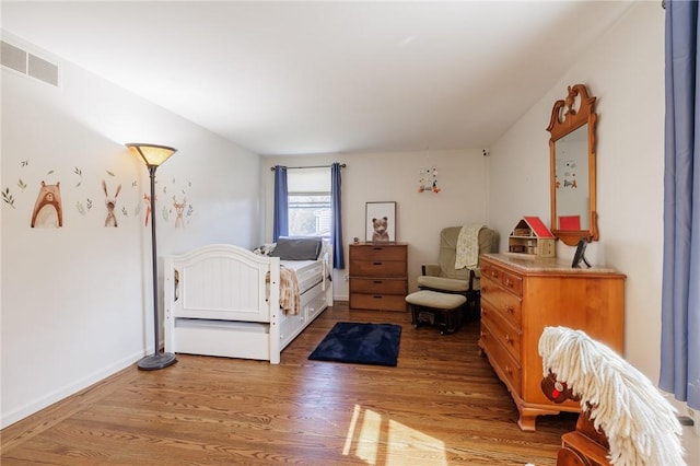 bedroom featuring visible vents, baseboards, and wood finished floors