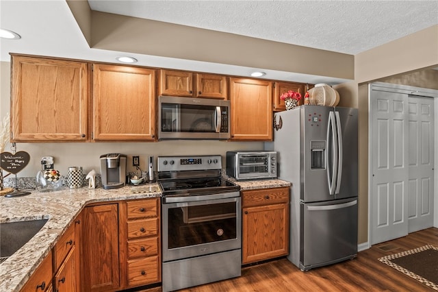 kitchen with dark wood finished floors, brown cabinetry, and stainless steel appliances