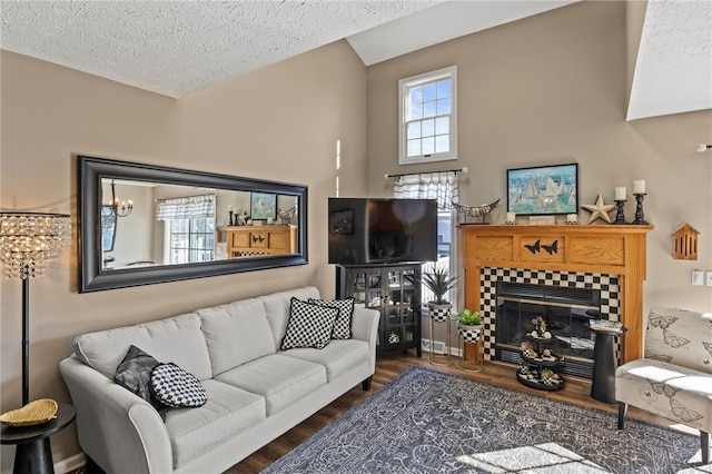 living area with a textured ceiling, wood finished floors, and a tile fireplace