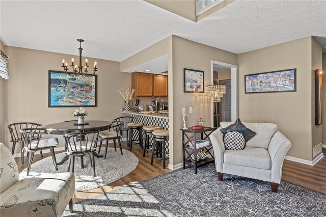 dining area featuring a chandelier, a textured ceiling, baseboards, and wood finished floors