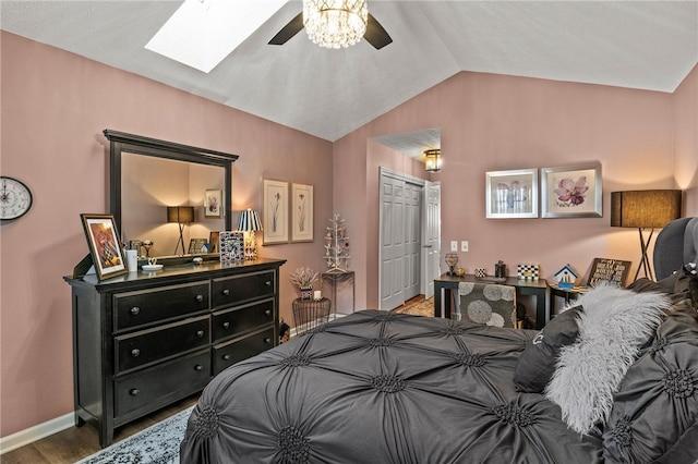 bedroom with a ceiling fan, wood finished floors, a closet, vaulted ceiling with skylight, and baseboards