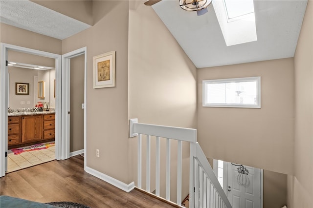 stairway with a ceiling fan, a skylight, wood finished floors, and baseboards